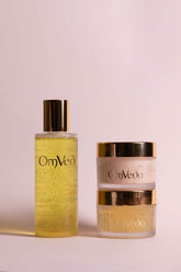 OmVeda golden skincare bottle and matching two-piece cream jars with gold caps