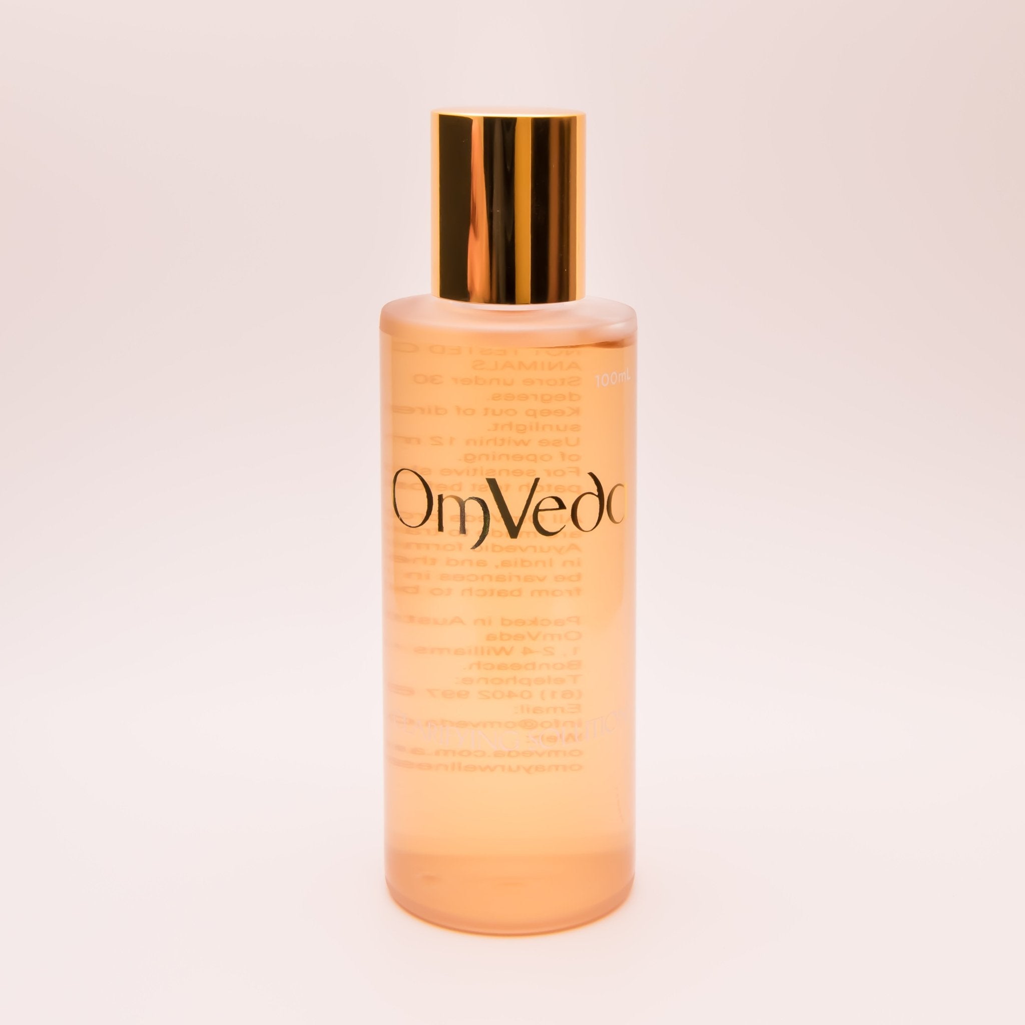 OmVeda clarifying solution 100ml translucent amber bottle with gold cap, front view