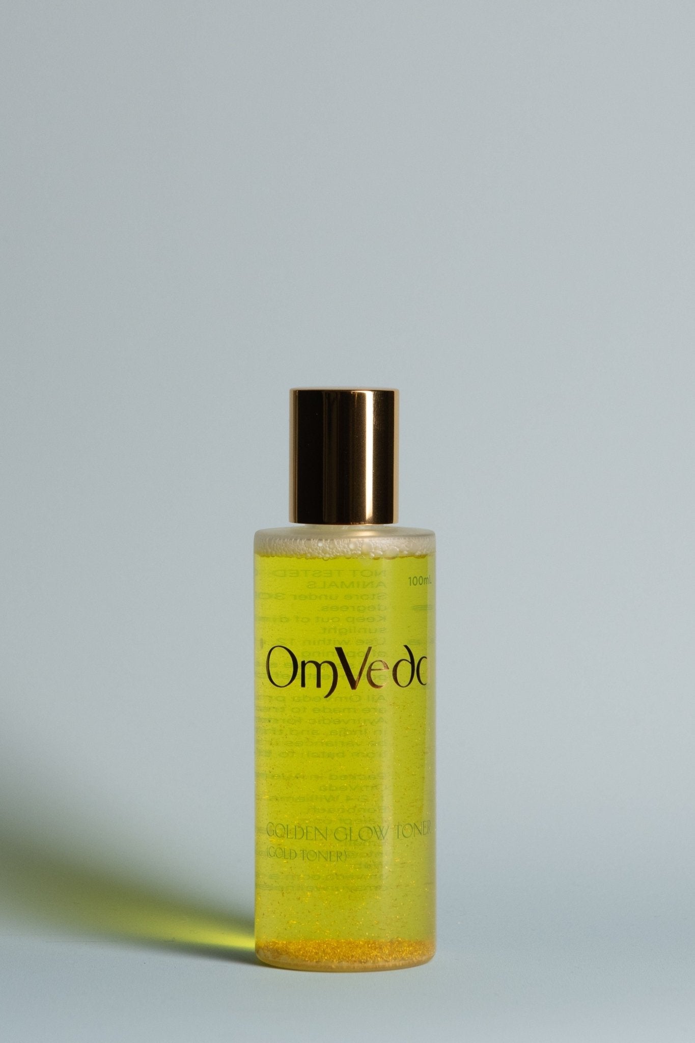 OmVeda Golden Glow toner bottle with gold cap, yellow translucent liquid