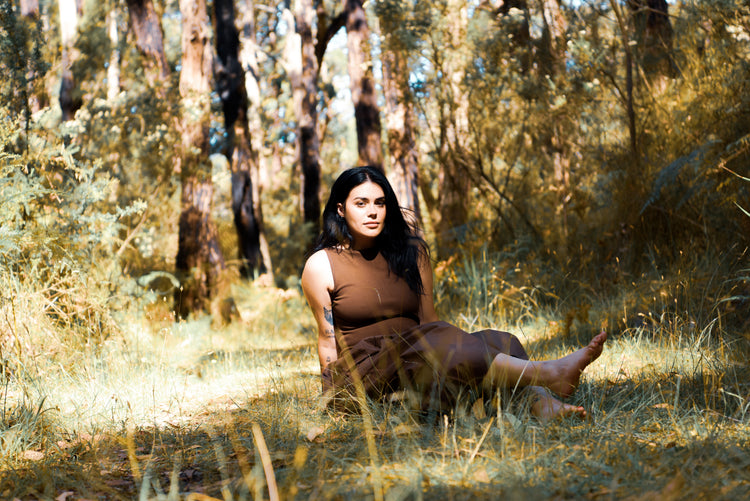 Brown sleeveless dress with belted waist on a model outdoors