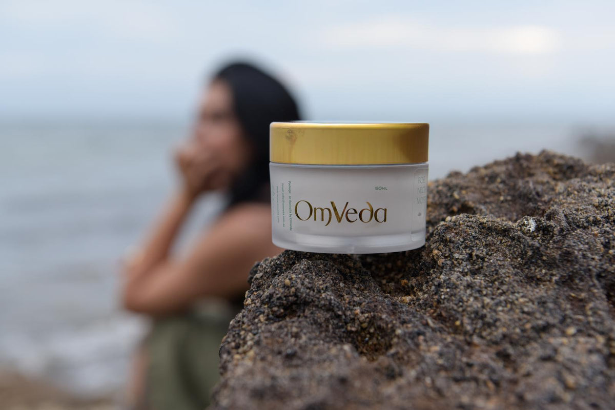 Jar of OmVeda product on a rock with a blurred person in the background