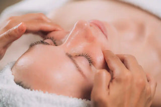 Someone receiving a facial massage or skincare treatment while lying on a white towel.