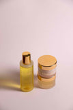 OmVeda yellow skincare bottle with pump and two small gold-lidded jars