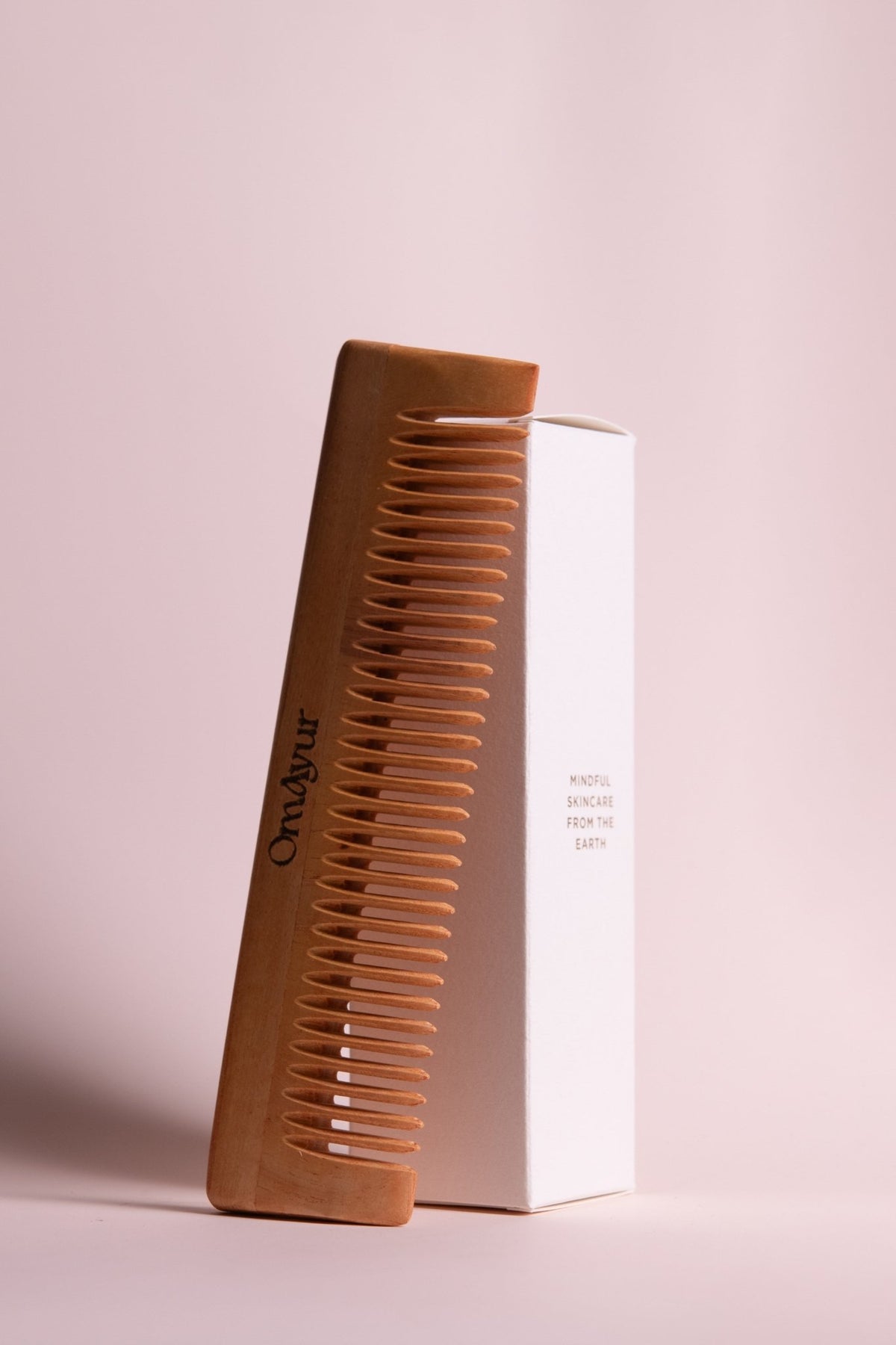 Brown hair comb with fine teeth, shown with white product box