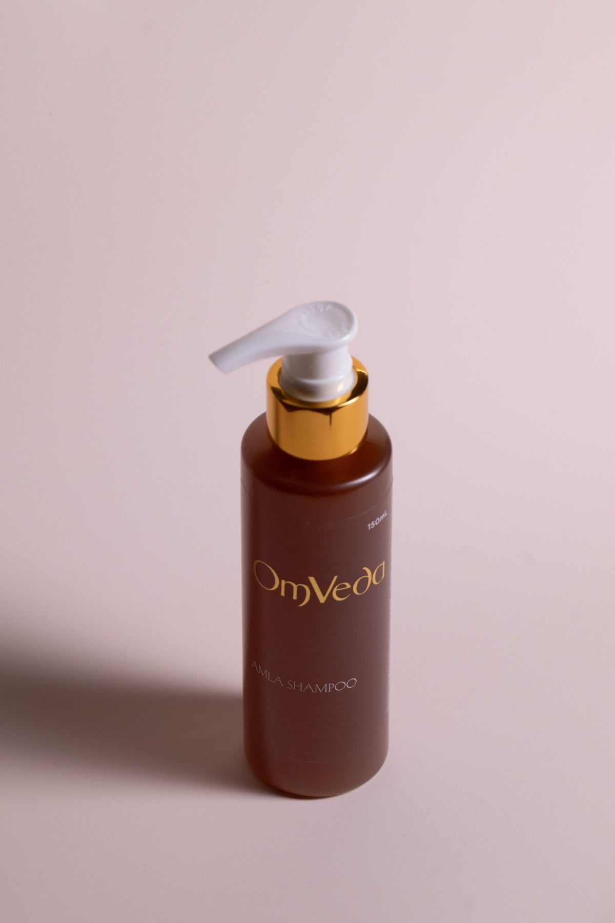 OmVeda amla shampoo bottle with pump, brown bottle and white dispenser