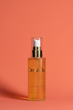 OmVeda calming body oil in amber glass bottle with spray pump top