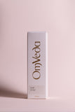 OmVeda hair tonic box, white packaging with brown logo text