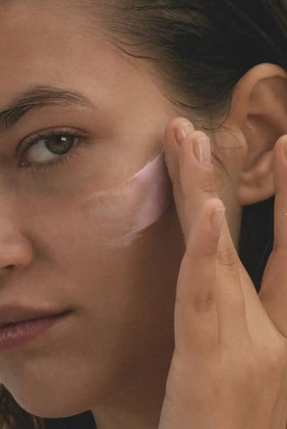 Pink under-eye patches or masks being applied to the skin.