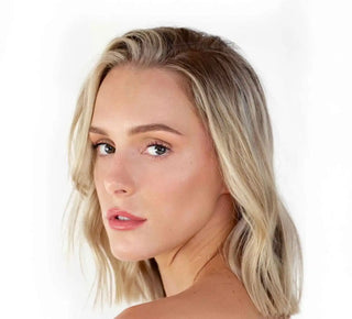 A side profile portrait featuring blonde wavy hair, natural makeup, and pink lips.